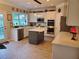 White kitchen with tile floors, gray island, stone backsplash, and stainless steel appliances at 101 Brendylynn Trce, Woodstock, GA 30188