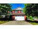 Two-story brick home featuring a two-car garage and a well-manicured lawn with mature trees at 417 Bell Flower Trl, Locust Grove, GA 30248