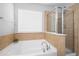 Bathroom with a bathtub and shower surrounded by tile, featuring a window for natural lighting at 101 Magnolia Creek Dr, Canton, GA 30115