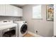 A laundry room with white cabinets and a window, featuring a front-load washer and dryer at 101 Magnolia Creek Dr, Canton, GA 30115