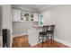 Bar area featuring a white countertop, dark metal bar stools, white cabinets, and hardwood floors at 3460 Highgate Hills Ne Dr, Duluth, GA 30097