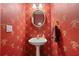 Powder room featuring red wallpaper, a pedestal sink, and a decorative mirror at 3460 Highgate Hills Ne Dr, Duluth, GA 30097