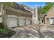 Stone and brick home exterior showcasing a three car garage and well-maintained landscaping at 4340 Candacraig, Johns Creek, GA 30022