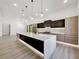 Modern kitchen featuring black and wood cabinetry, a large island with a sink, and modern lighting at 191 Darwish Dr, Mcdonough, GA 30252