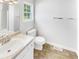 Well-lit bathroom featuring a clean white sink, toilet, tile flooring, and a window at 45 Carroll St, Temple, GA 30179