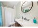 Well-lit bathroom featuring a single sink vanity with round mirror and a shower with a stylish blue patterned curtain at 725 Crab Orchard Ct, Roswell, GA 30076