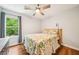 Bedroom featuring hardwood floors, ceiling fan, and natural light from a window overlooking lush greenery at 725 Crab Orchard Ct, Roswell, GA 30076