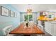 Bright dining area with a long wooden table, white chairs, and a view of the modern kitchen and backyard at 725 Crab Orchard Ct, Roswell, GA 30076