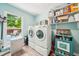Well-organized laundry room with washer, dryer, shelving, and natural light at 725 Crab Orchard Ct, Roswell, GA 30076