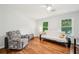 Cozy living room with a recliner, futon, hardwood floors, and natural light from two windows at 725 Crab Orchard Ct, Roswell, GA 30076