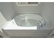 Close-up of a gleaming white garden tub featuring a tile base and modern chrome fixtures at 490 Charleston Pl, Villa Rica, GA 30180