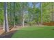 Lush green backyard featuring manicured lawn, mature trees, and partial fence at 823 Valley Dr, Canton, GA 30114