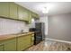 A stylish kitchen features modern stainless appliances and green cabinets with wood countertop at 1290 Campbellton Sw Rd, Atlanta, GA 30310