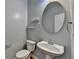 Contemporary half bathroom with a pedestal sink, oval mirror, and updated fixtures at 702 Village Field Ct, Suwanee, GA 30024