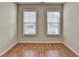 This bedroom has wood flooring and two bright windows with horizontal blinds at 702 Village Field Ct, Suwanee, GA 30024