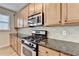 Well-equipped kitchen featuring granite counters, wooden cabinets, and stainless steel appliances at 702 Village Field Ct, Suwanee, GA 30024