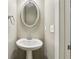 Cozy powder room featuring a pedestal sink, oval mirror, and neutral color scheme, offering simple elegance at 737 St Charles Ne Ave, Atlanta, GA 30306
