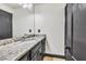 Bathroom features granite countertop on vanity with gray cabinets and framed mirror at 401 Sara Ct, Loganville, GA 30052