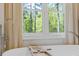 Close-up of a bathtub by a window with neutral striped curtains and a treetop view at 4067 Randall Farm Se Rd, Atlanta, GA 30339