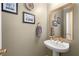 Chic powder room with pedestal sink, gold fixtures, and decorative mirror at 11060 Pennbrooke Xing, Johns Creek, GA 30097