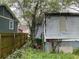 Backyard view with overgrown grass, adjacent building and a partially fenced yard at 1254 Campbellton Sw Rd, Atlanta, GA 30310