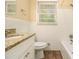 Bathroom showcasing white cabinets, granite countertop, window, toilet, and a tiled bathtub at 3500 Finesse Dr, Decatur, GA 30032