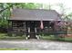 Cozy log cabin featuring a welcoming front porch, stone chimney, and a quaint, woodsy setting at 6503 Old Macon Hwy, Rex, GA 30273