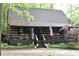 Charming log cabin-style home with a covered front porch and stone chimney, perfect for rustic living at 6503 Old Macon Hwy, Rex, GA 30273