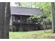 Charming two-story log cabin nestled among trees, featuring a stone foundation and inviting front porch at 6503 Old Macon Hwy, Rex, GA 30273