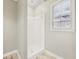 Bathroom featuring white tile shower, window, and neutral walls at 2667 Fieldstone Se Dr, Conyers, GA 30013