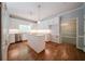 White kitchen with an island, wooden floors, pendant lights, stainless appliances, and a view to the next room at 4320 Royal Mustang Way, Snellville, GA 30039
