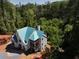 A new house under construction showing the roof covered in blue protective sheathing, surrounded by lush greenery at 469 Emily Reed Ln, Atlanta, GA 30342