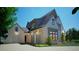 Luxury home featuring gray brick, dark framed windows, arched entryway, and a driveway with a three-car garage at 469 Emily Reed Lot 11 Ln, Atlanta, GA 30342