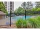 View of a large community pool, surrounded by mature trees and secured by a black metal fence for privacy at 799 Hammond Dr # 314, Atlanta, GA 30328