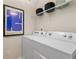 Practical laundry area with a modern washer and dryer, shelving, and stylish artwork at 8214 Tiger Way, Riverdale, GA 30296