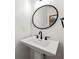 Stylish bathroom with a pedestal sink, round black mirror, and modern fixtures at 113 Courtyard Ter, Roswell, GA 30075