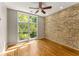 Bedroom featuring exposed brick wall, hardwood floors, and a large window offering natural light at 1290 Fernwood Ne Cir, Brookhaven, GA 30319