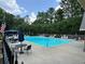 Community pool with lounge chairs and umbrellas next to a clubhouse, all surrounded by mature landscaping at 602 Springharbor Dr, Woodstock, GA 30188
