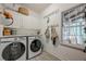 Well-lit laundry room with modern washer and dryer, storage cabinets, and a view of the outdoors at 745 Amberton Close, Suwanee, GA 30024