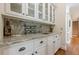 Wet bar area with granite countertop, white cabinets, and tile backsplash at 1655 Holly Lake Cir, Snellville, GA 30078