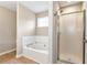 Bright bathroom featuring a white tub with tile backsplash and a glass shower enclosure at 2875 Riverbend Ct, Snellville, GA 30078