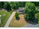 An aerial view of a well-manicured home with a long driveway, mature trees, and beautiful green lawn at 3987 Ivory Gables Pl, Buford, GA 30519