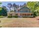 Charming two-story home featuring a brick facade, green siding, a covered front porch, and a well-manicured lawn at 3987 Ivory Gables Pl, Buford, GA 30519