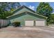 Exterior shot of a home's two-car garage with green siding, surrounded by well-maintained landscaping at 3987 Ivory Gables Pl, Buford, GA 30519