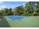 Enjoy the community's well-maintained blue and green tennis courts surrounded by lush greenery on a sunny day at 4628 Mountain Creek Ne Dr, Roswell, GA 30075