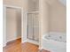 Bright bathroom featuring wood floors, shower with glass door, and large soaking tub at 362 Interlake Pass, Mcdonough, GA 30252