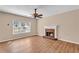 Cozy living room featuring a brick fireplace, hardwood floors, a ceiling fan, and large windows at 362 Interlake Pass, Mcdonough, GA 30252