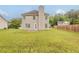 A view of the back of the home with a large grassy backyard and a wooden privacy fence at 4139 Kensington Cv, Atlanta, GA 30349