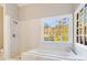 This bathroom offers a luxurious bathtub and separate shower with a large grid window to the backyard at 415 Collegiate Dr, Powder Springs, GA 30127