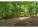Scenic view of a lush backyard with mature trees and a carpet of fallen leaves at 1811 Fountain Hill Ct, Duluth, GA 30097